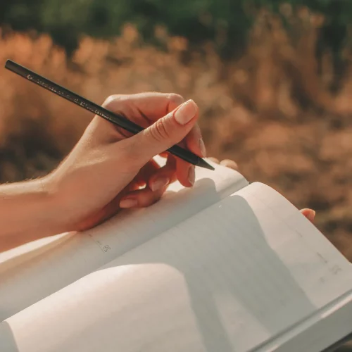 eine weibliche Hand mit eine Bleistift in der hand. Etwas wird in ein Notizbuch gezeichnet